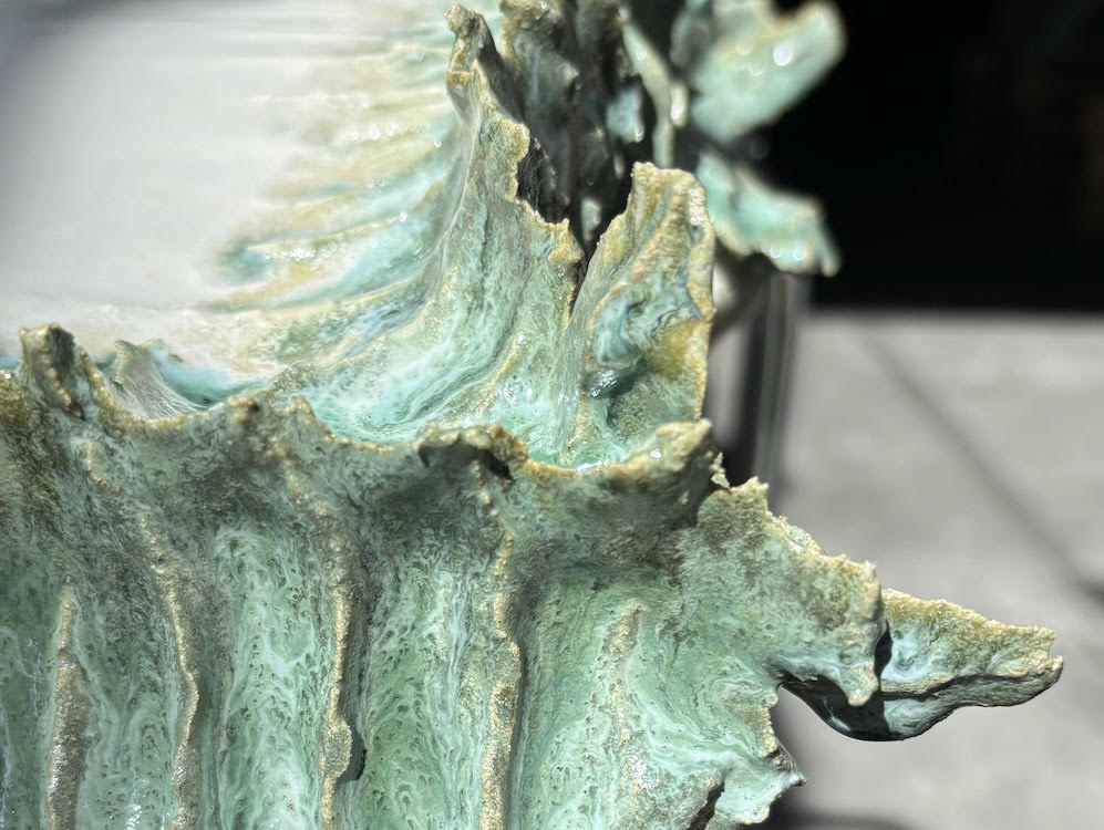 a close-up image of a ceramic work in white and green tones